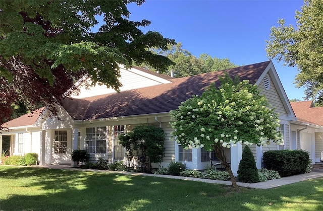 view of front of house with roof with shingles and a front lawn