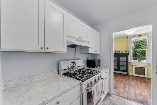 76 Dehaven Dr Unit 3D, Yonkers, NY 10703 - kitchen featuring light wood-type flooring, range with gas stovetop, under cabinet range hood, black microwave, and white cabinets