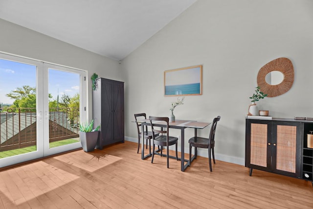 dining space featuring baseboards, wood finished floors, and high vaulted ceiling