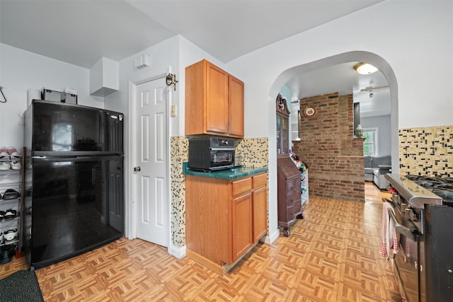 2 Random Rd, Greenwood Lake, NY 10925 - kitchen with gas stove, arched walkways, decorative backsplash, freestanding refrigerator, and brown cabinetry