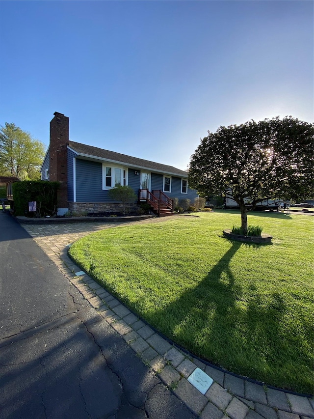 ranch-style house featuring a chimney and a front lawn