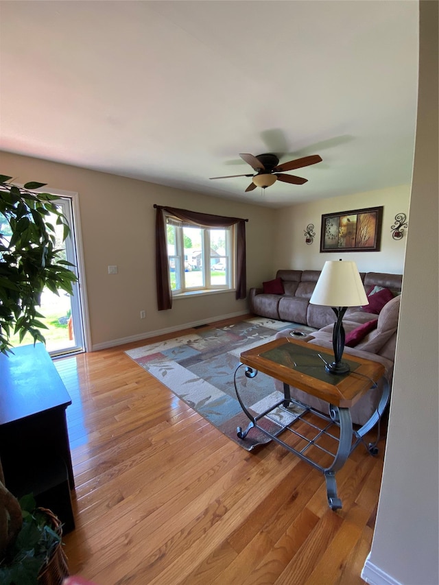 living area featuring baseboards, ceiling fan, and wood finished floors