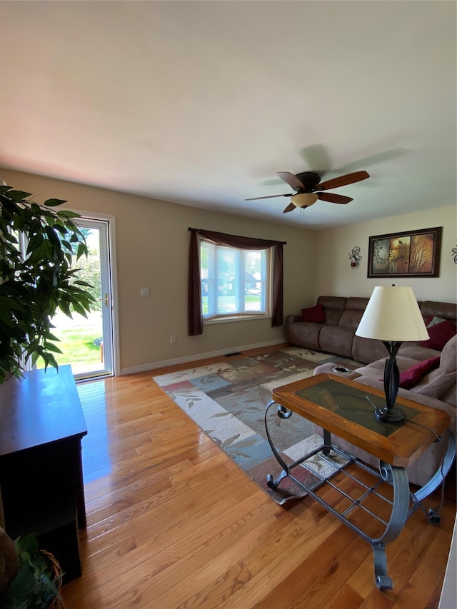 living area with baseboards, a ceiling fan, and wood finished floors