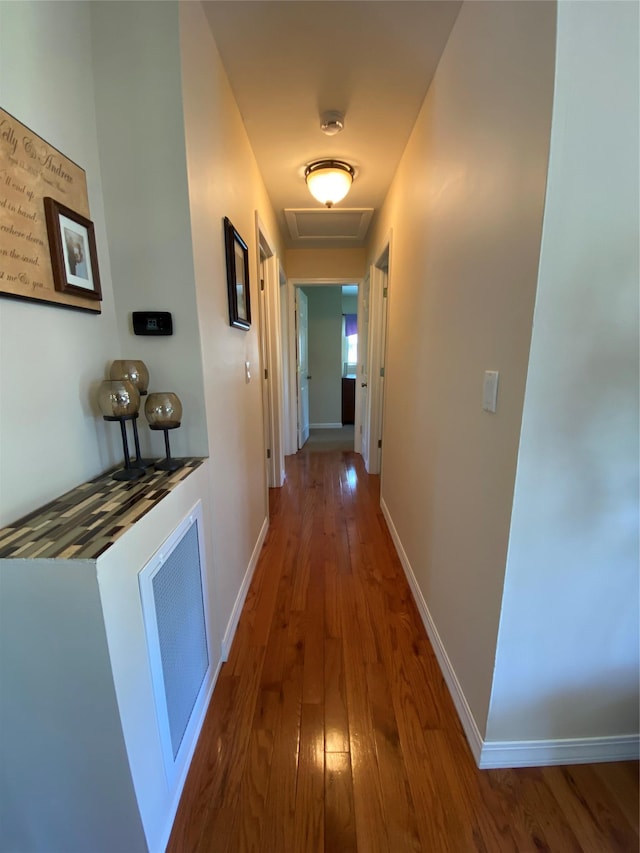 hallway with baseboards, visible vents, attic access, and hardwood / wood-style floors