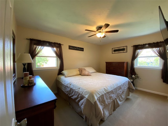 bedroom with baseboards, multiple windows, light carpet, and ceiling fan