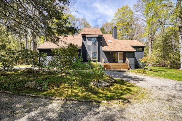 view of front of property featuring roof with shingles, a chimney, and a front yard