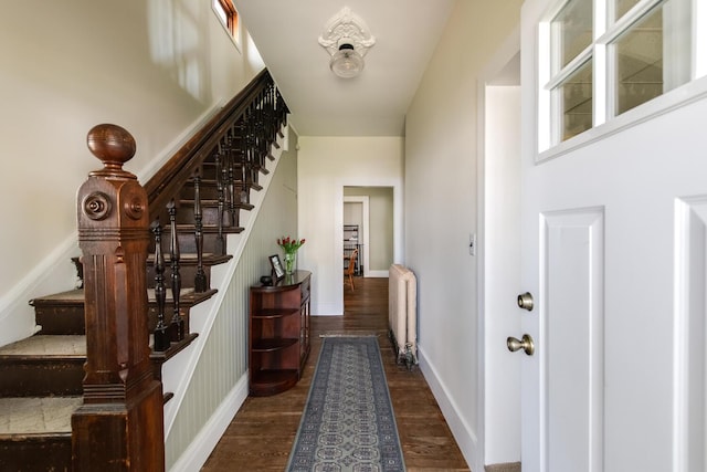 interior space featuring baseboards, dark wood finished floors, radiator heating unit, and stairway