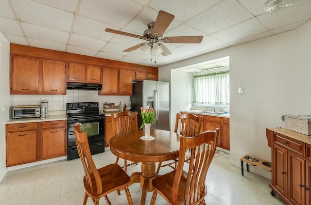 kitchen with black electric range, a sink, stainless steel fridge, and light floors