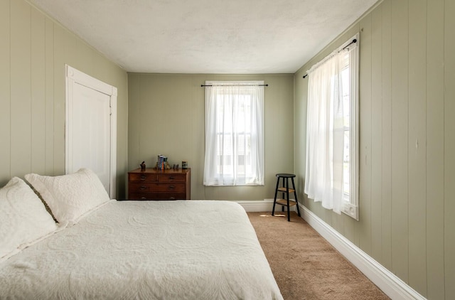 bedroom with light colored carpet, baseboards, and wooden walls