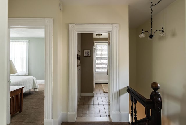 hallway with tile patterned floors, baseboards, a chandelier, and a wealth of natural light