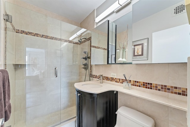 bathroom with toilet, vanity, visible vents, backsplash, and a shower stall