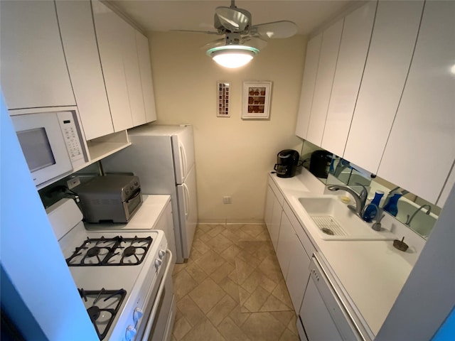 kitchen featuring ceiling fan, a sink, baseboards, white cabinets, and white appliances