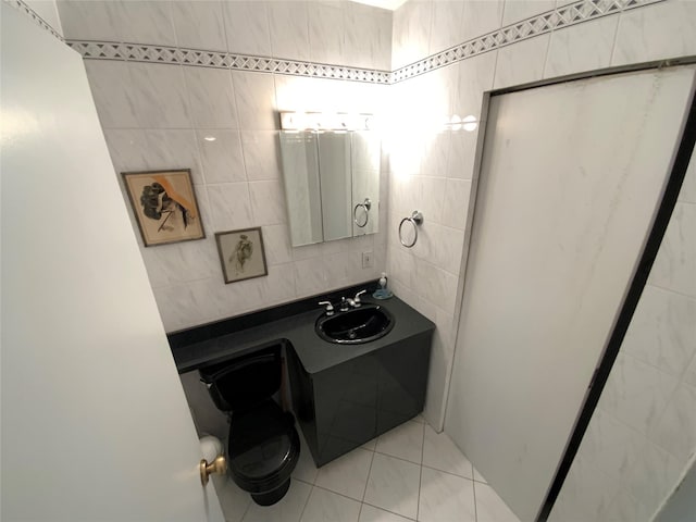bathroom featuring toilet, tile walls, a sink, and tile patterned flooring