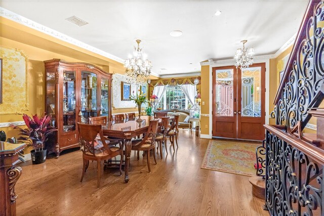 dining area featuring crown molding, a notable chandelier, wood finished floors, and visible vents