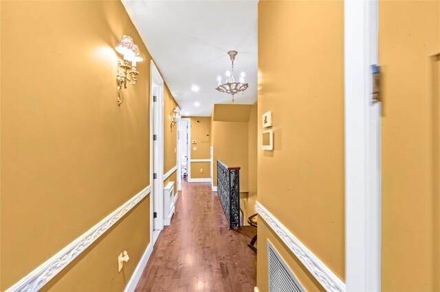 corridor featuring a chandelier, baseboards, an upstairs landing, and wood finished floors