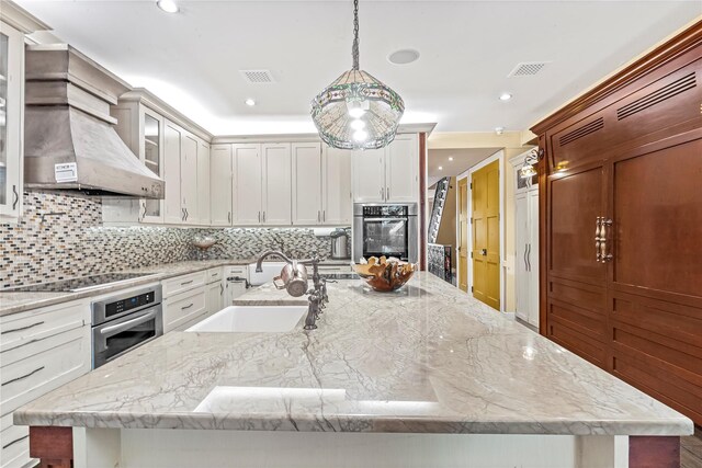 kitchen with visible vents, black electric stovetop, a spacious island, custom range hood, and a sink