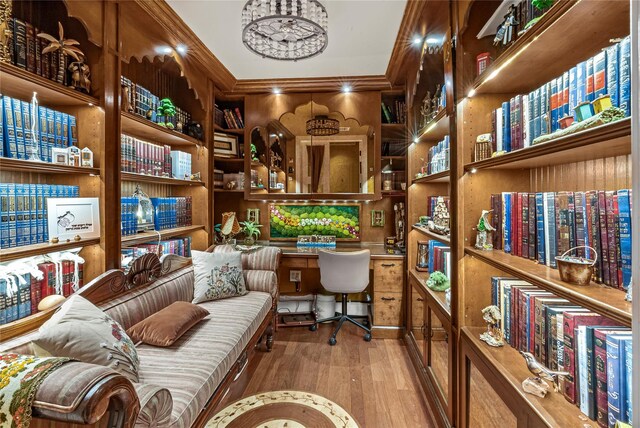 sitting room with ornamental molding, built in desk, and wood finished floors