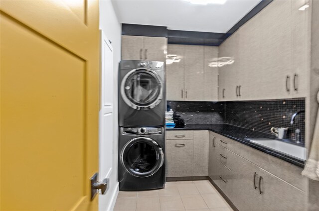 laundry room featuring laundry area, a sink, light tile patterned flooring, and stacked washer / dryer