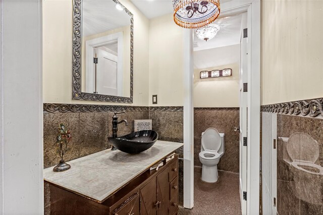 bathroom featuring tile walls, tile patterned flooring, wainscoting, vanity, and toilet