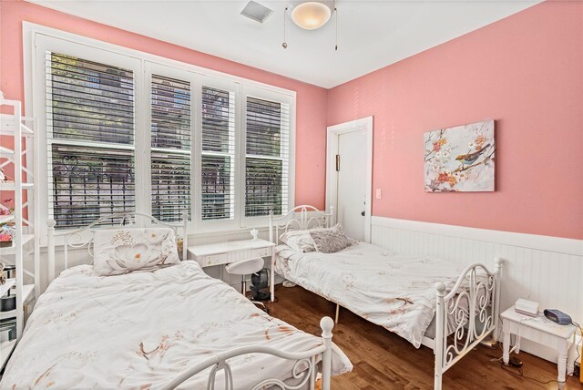 bedroom featuring a wainscoted wall and wood finished floors