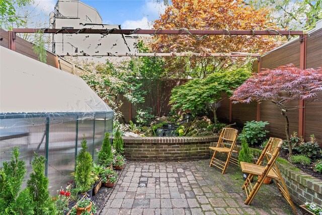 view of patio / terrace with fence, an outbuilding, and a greenhouse