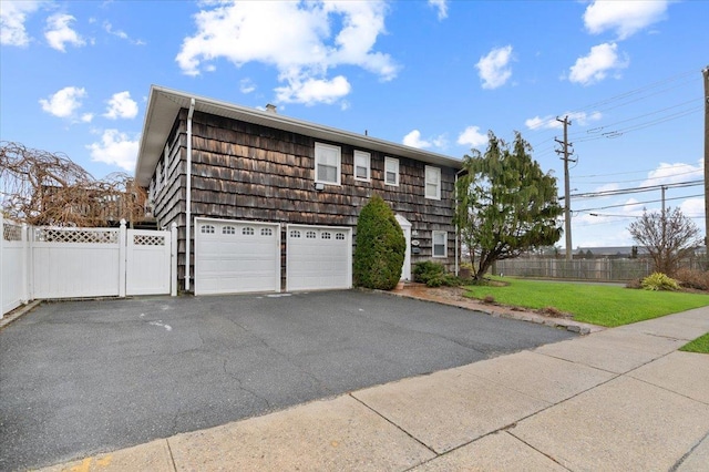 view of front facade featuring a garage, fence, driveway, and a front yard