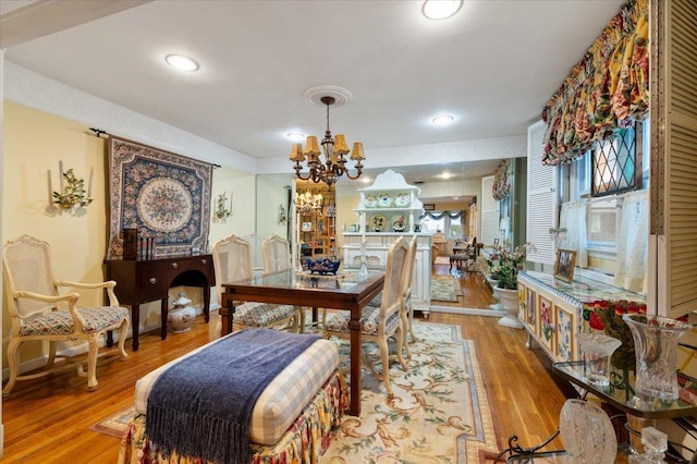 dining space with recessed lighting, an inviting chandelier, and wood finished floors