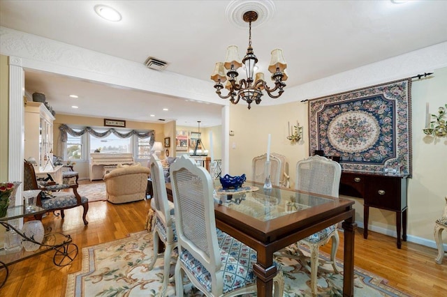 dining area featuring baseboards, visible vents, light wood finished floors, and a chandelier