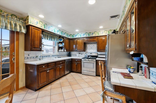 kitchen featuring appliances with stainless steel finishes, tile counters, decorative backsplash, visible vents, and ornamental molding