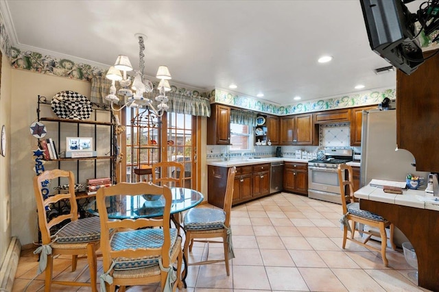 kitchen featuring crown molding, stainless steel appliances, a notable chandelier, and light tile patterned floors