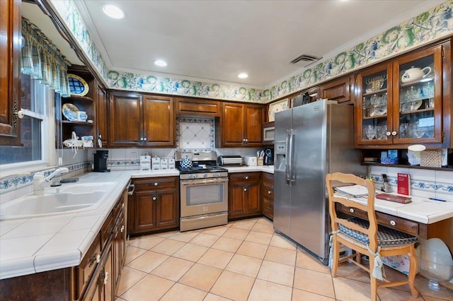 kitchen featuring light tile patterned flooring, appliances with stainless steel finishes, a sink, tile countertops, and visible vents
