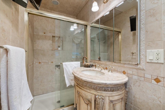 bathroom with vanity, a stall shower, and tile walls