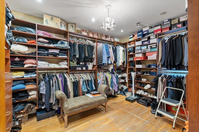 spacious closet featuring wood finished floors and a chandelier