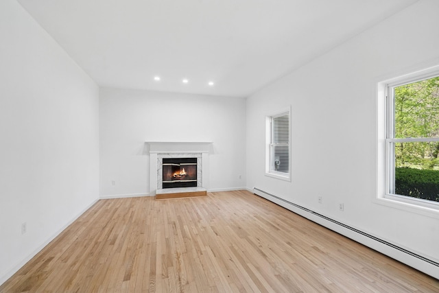 unfurnished living room featuring baseboards, recessed lighting, a high end fireplace, a baseboard radiator, and light wood-style flooring