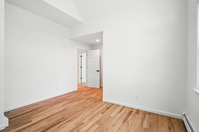 empty room with light wood-style floors, baseboards, and a baseboard radiator