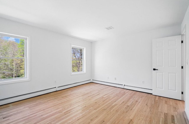 spare room with visible vents, light wood-style flooring, and a baseboard heating unit