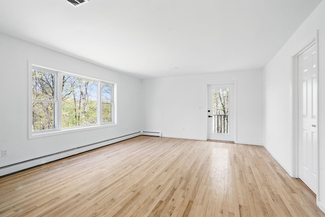 spare room featuring a healthy amount of sunlight, baseboards, a baseboard radiator, and light wood-style floors