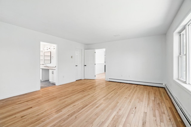 unfurnished living room featuring a sink, baseboards, a baseboard radiator, and light wood-type flooring