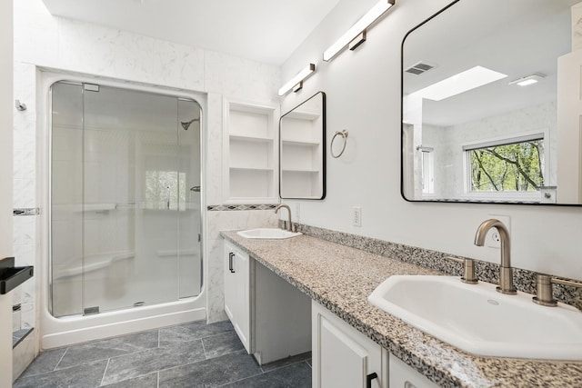 bathroom with a sink, a skylight, a stall shower, and visible vents