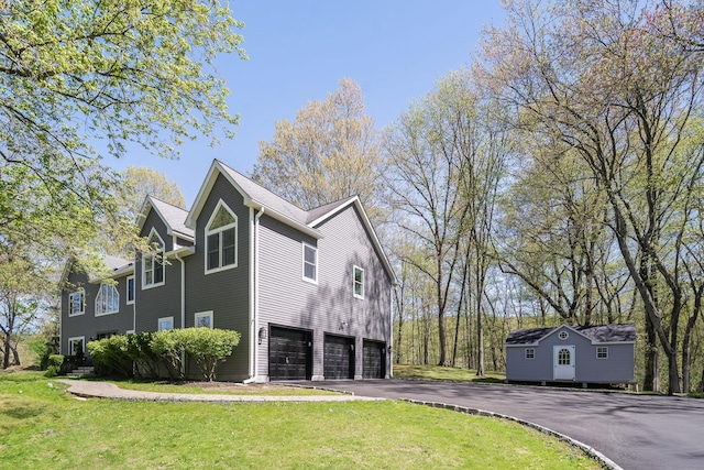 view of side of property featuring a garage, a lawn, and driveway