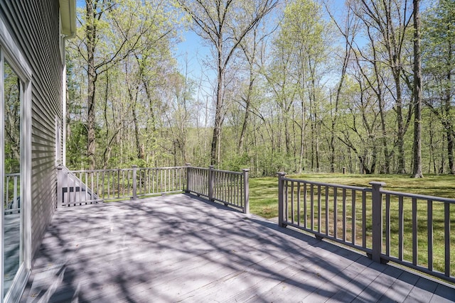 wooden terrace featuring a view of trees and a yard