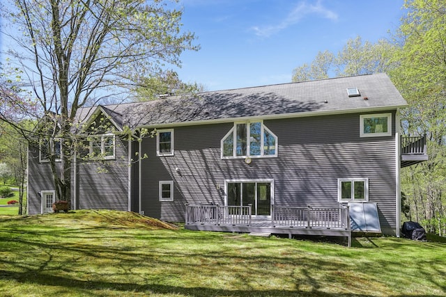 rear view of property featuring a lawn and a wooden deck