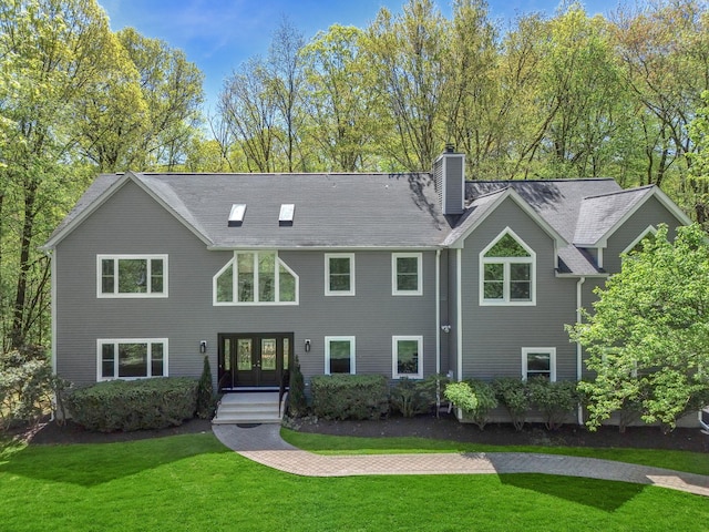 view of front facade with a chimney, french doors, and a front lawn