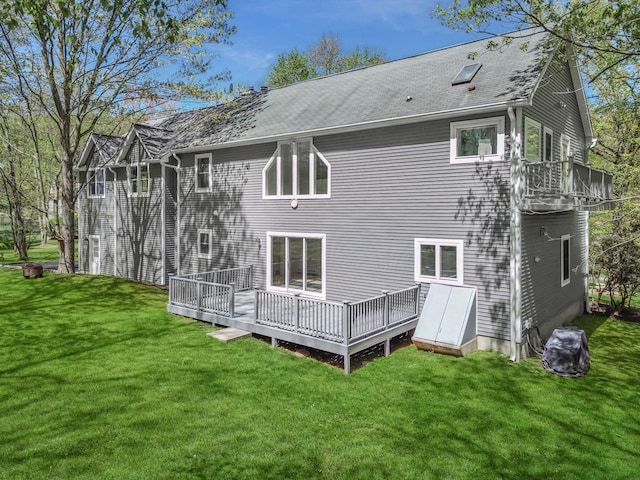 rear view of house with a lawn, a wooden deck, and a shingled roof