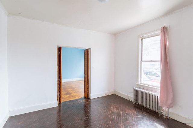empty room featuring radiator, ornamental molding, and baseboards