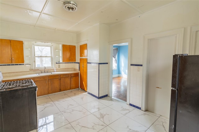 kitchen with plenty of natural light, brown cabinetry, range with electric cooktop, a sink, and freestanding refrigerator
