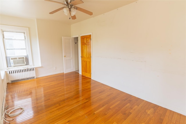 spare room featuring radiator, ceiling fan, cooling unit, and light wood-style flooring