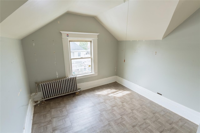 additional living space with baseboards, radiator, and vaulted ceiling