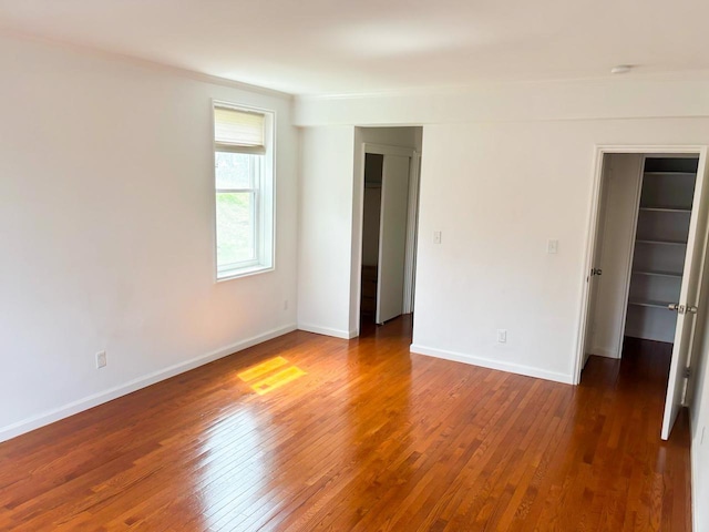 spare room featuring crown molding, baseboards, and wood-type flooring