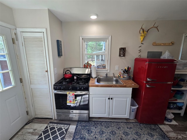 kitchen featuring white cabinets, gas stove, and a sink